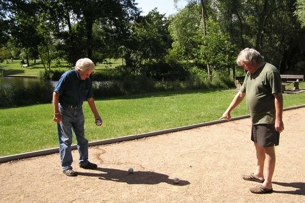 Zwei Boule Spieler bei der Kontrolle der Kugeldistanz auf der Boule-Bahn