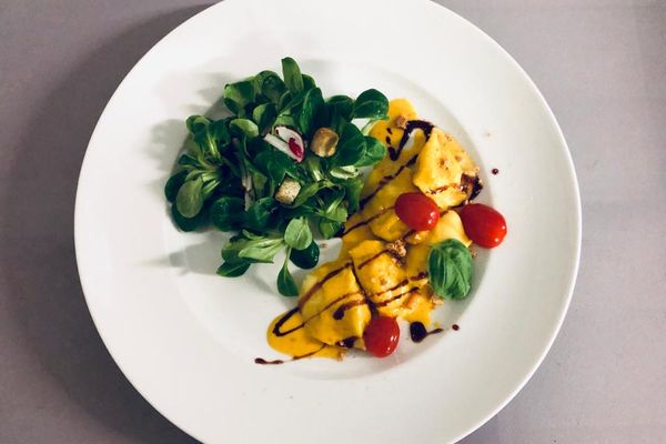 Ein Teller mit appetitlich angerichteten Kürbisravioli mit Beilagensalat.