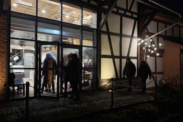 Es ist Nacht und einige Besucher gehen durch die große, gläserne Eingangstür des Schlossmuseums Romrod.