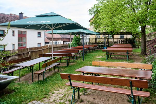 Blick in den mit Biertischen und Bierbänken ausgestatteten Biergarten.