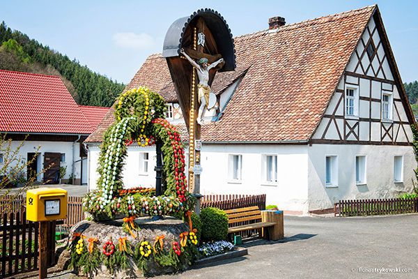 Vor einem Fachwerkhaus steht ein geschmückter Osterbrunnen.