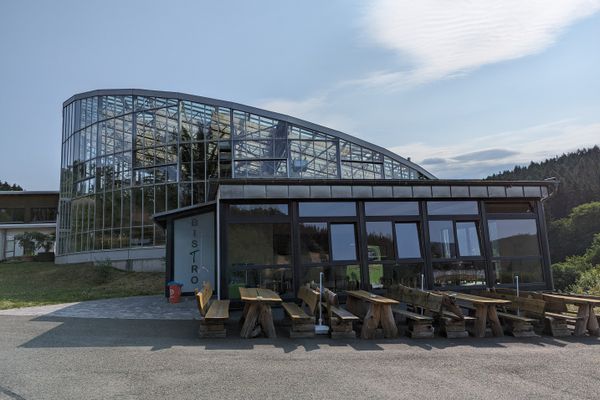 Das Bild zeigt im Hintergrund das Tropenhaus Klein Eden. Davor ist das dazugehörige Bistro zu sehen.