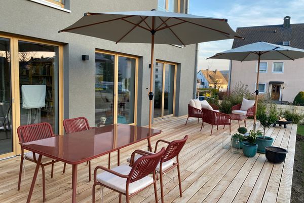 Blick auf die Terrasse mit Sitzgruppe im Hintergrund und Esstisch mit vier Stühlen im Vordergrund