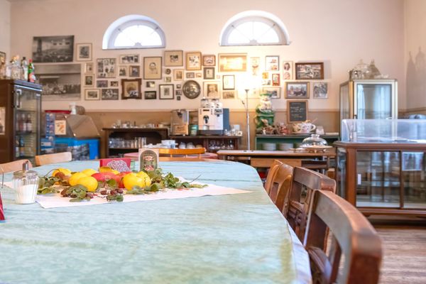 Großer Tisch mit Dekoration, umgeben von Stühlen, im Raum mit Bildern an der Wand.