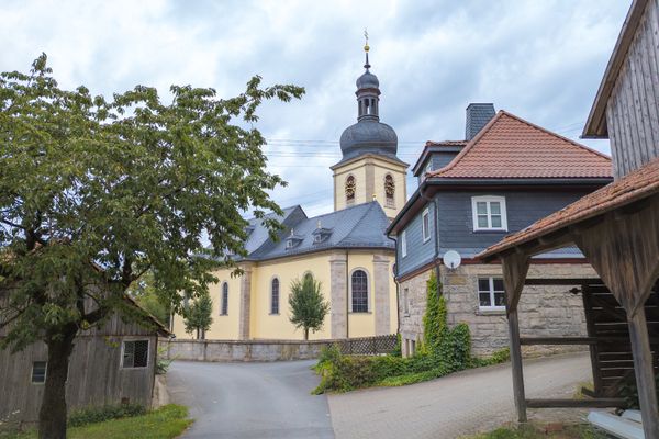 Das Bild zeigt die Außenansicht der Wallfahrtskirche Mariä Geburt in Glosberg. Man sieht die Kirchturmspitze und die Nebengebäude der Kirche.