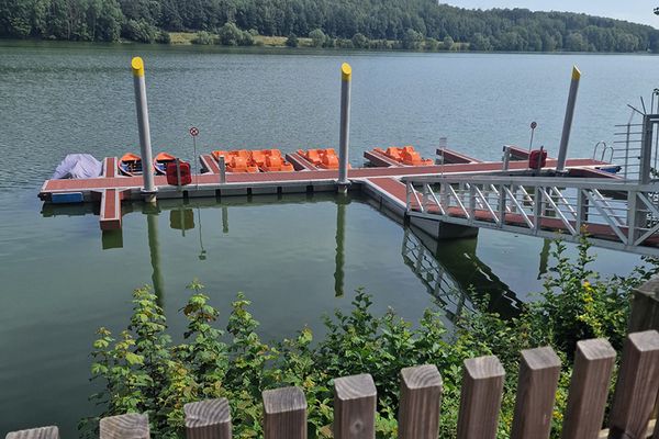 Langer Bootssteg auf einem See mit bunten Tret- und Ruderbooten