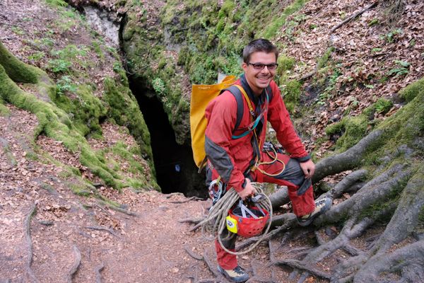 Höhlenguide mit Kletterausrüstung und Rucksack vor dem Einstieg in den Höhlenschacht