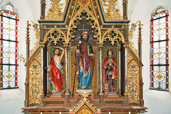 Ein Teil des Hochaltars mit Holzplastiken der Heiligen Jakobus, Florian und Sebastian. Links und rechts bemalte Kirchenfenster.