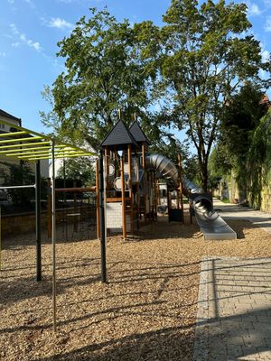 Das Bild zeigt eine Fitnessanlage zum Trainieren von Kraft aus Ausdauer für ältere Kinder. Auch sieht man den Kletterturm mit Röhrenrutsche. Diese befinden sich am Spielplatz im Stadtgraben in Kronach.