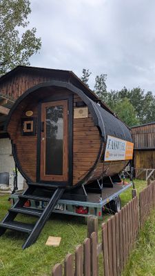 Auf dem Bild ist die mobile Fass-Sauna von außen, im Außenbereich stehend, zu sehen.