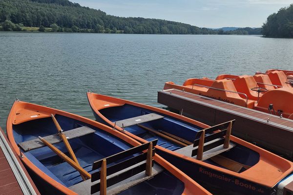 Bunte Ruderboote liegen am Steg auf einem See