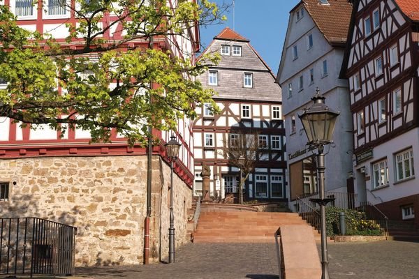 Blick eine Sandsteintreppe empor auf einige schön restaurierte Fachwerkhäuser.