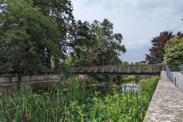 Das Bild zeigt den Fluss Kronach mit der der Brücke "Schwarzer Steg". Dies befindet sich am ehemaligen Landesgartenschau-Gelände in Kronach.