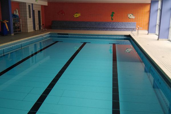 Schwimmbecken mit vier Bahnen, orange gestrichene Wand im Hintergrund