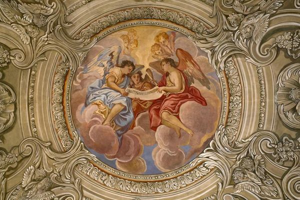 Prächtiges Deckengemälde in der Karmelitenkirche Straubing: Drei große Engel halten, auf Wolken sitzend, eine Schriftrolle. Kleinere Engel blicken auf sie herab.