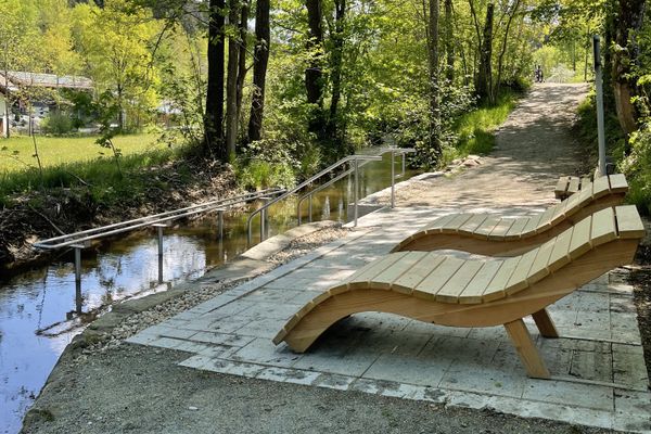 Zwei hölzerne Schwungliegen vor einer Wassertretanlage im Laubwald.