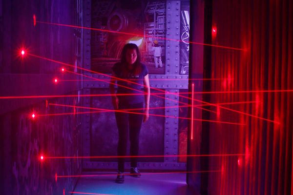 Eine Besucherin kämpft sich durch einen Irrweg aus roten Laserstrahlen.