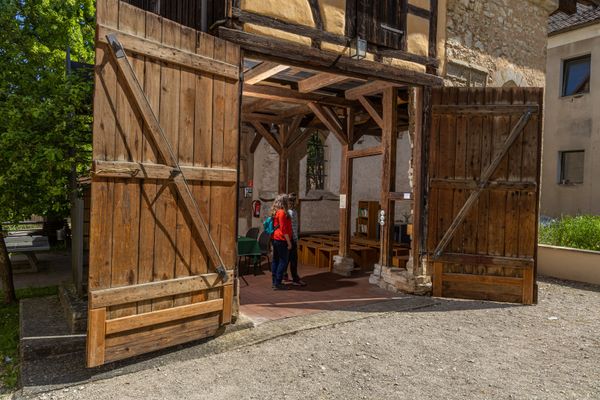 Zwei Frauen stehen in der alten aber restaurierten St. Willibalds Kapelle. Die Kapelle sieht einer schönen Scheune ähnlich und hat ein großes hölzernes Scheunentor und Fachwerk.
