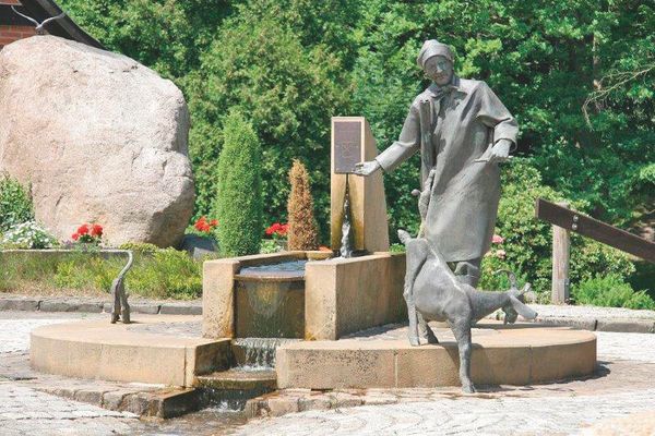 Der Brunnen mit Denkmal von Grefel Dorjen mit Ihren Gefährten, einer Ziege und einer Katze auf dem Marktplatz in Dorfmark bei Bad Fallingbostel