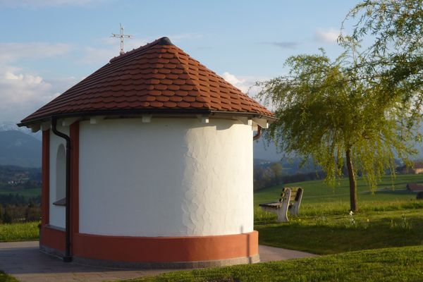 Die kleine Kapelle am östlichen Ortsrand von Schönberg steht direkt vor der eindrucksvollen Kulisse der Alpenkette.