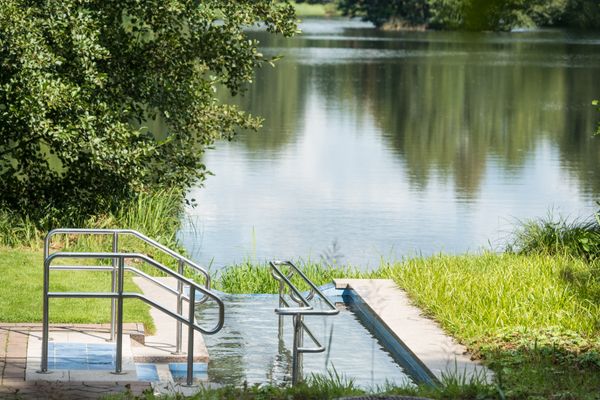 Im Hintergrund ist ein See des Kurparks am See zu sehen, im Vordergrung das Kneipp Tretbecken