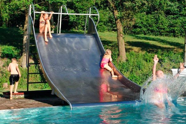 Auf der breiten Edelstahl-Wasserrutsche stürzen sich junge Badegäste ins kühle Nass.