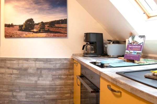 Küchenzeile mit Herd, Kaffeemaschine und Arbeitsplatte unter schräger Decke mit Dachfenster