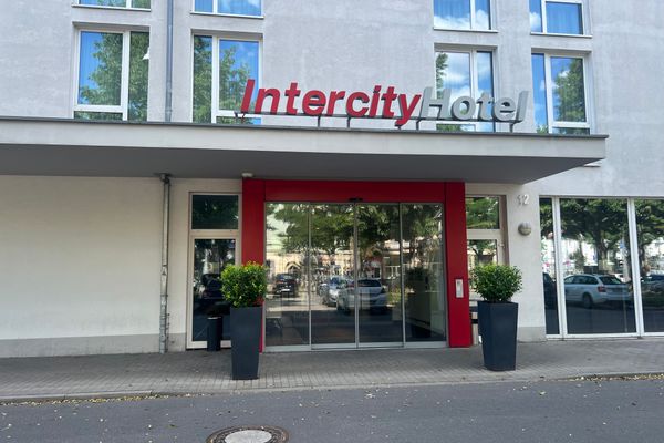 Eingang eines Hotels mit Glas-Schiebetüren, rotem Rahmen und Schriftzug ‘Intercity Hotel‘ über dem Vordach